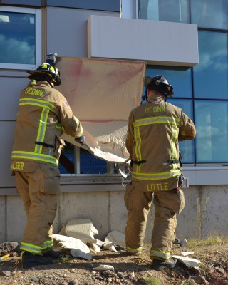Firefighters Michael Alger and Brian Little breach a wall to find metal studs. (Chris DeFrancesco/UConn Health)