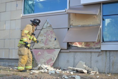 Firefighter David Demarest scrapes away at insulation. Cutting in a triangular shape can help maintain a wall’s structural integrity. (Chris DeFrancesco/UConn Health)